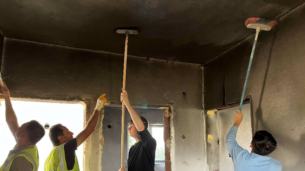 Yangın sonrası kullanılamaz hale gelen evi öğrencilerle onarıyor