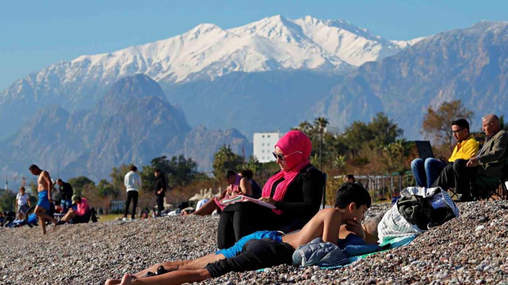 Antalya’da 2025 ikl gününde  karla kaplı dağların gölgesinde deniz ve güneş keyfi